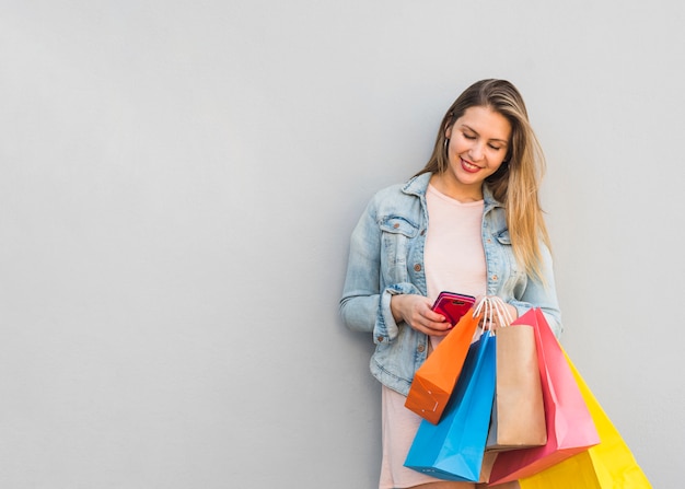 Free Photo | Pretty woman with shopping bags using smartphone