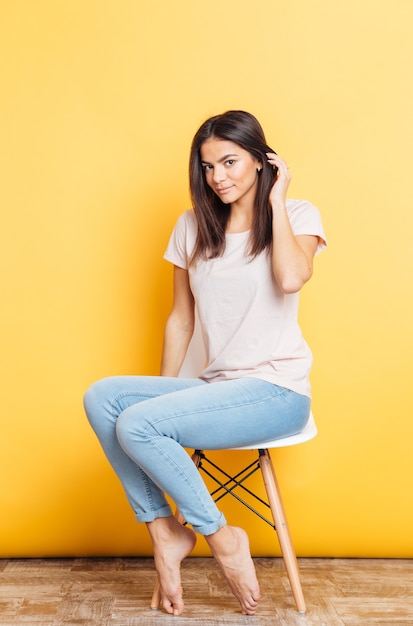 Premium Photo Pretty Young Woman Sitting On The Chair Over Yellow Wall