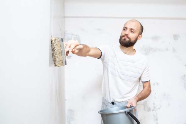 Premium Photo | Priming the wall with a brush for renovation work ...