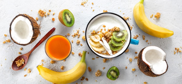 Probiotic food concept. bowl of homemade coconut yogurt with granola and fresh fruits on light background top view. healthy vegan food. tasty and healthy breakfast Premium Photo