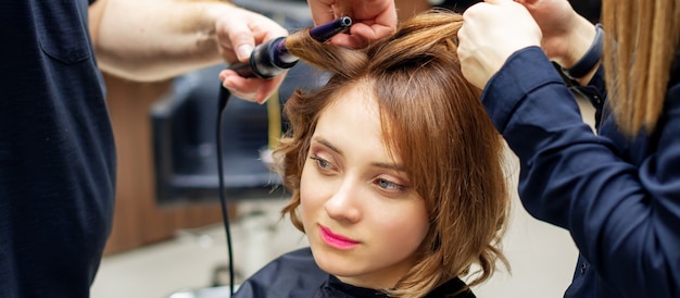 Premium Photo | Professional hairdresser twists curls of long light ...