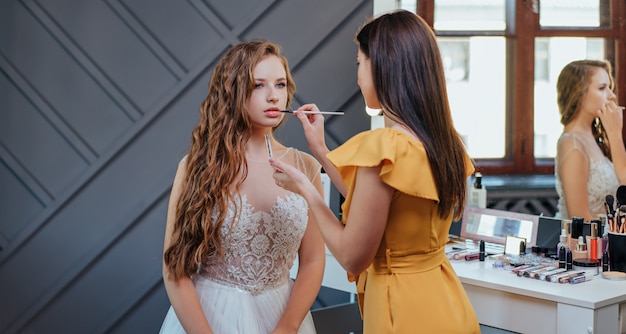 Professional makeup and hairstyle artist making makeup for the bride. professional cosmetics Premium