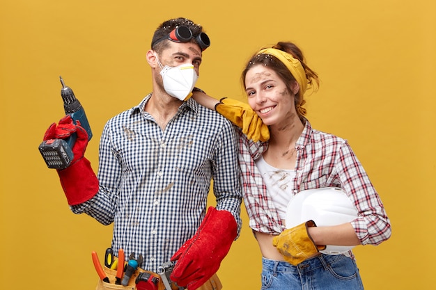 professional-male-manual-worker-wearing-protective-eyewear-head-mask-gloves-holding-drilling-machine-fixing-something-his-colleague-female-with-dirty-face-having-happy-expression_273609-7940 İnşaat Malzemeleri Fiyatları 2021 Yılı Güncelleme