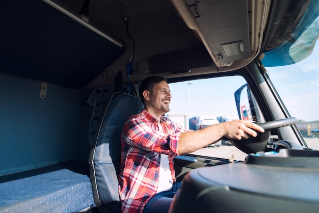 Professional middle aged truck driver in casual clothes driving truck vehicle and delivering cargo to destination Free Photo
