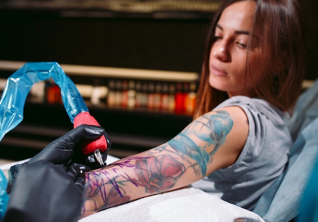 Premium Photo | Professional tattoo artist makes a tattoo on a young ...