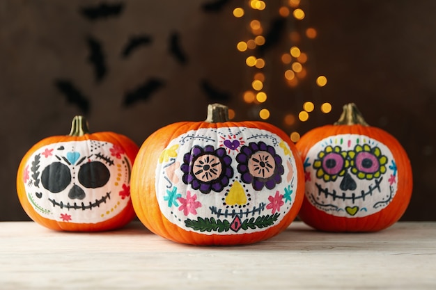 Premium Photo | Pumpkins with catrina skull makeup on brown with ...