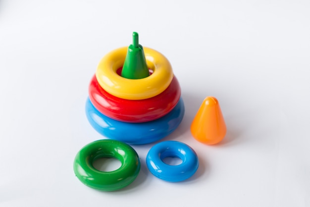 Pyramid build from colored rings with a clown head on top. toy for babies and toddlers to joyfully learn mechanical skills and colors. studio shot on white. Premium Photo