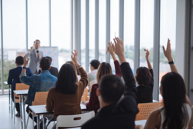 Raised up hands and arms of large group in seminar class room to agree with speaker at conference seminar meeting room Premium Photo