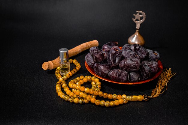 Ramadan kareem mubarak islamic dark surface with dates, prayer beads, miswak, itar and antimony, cop