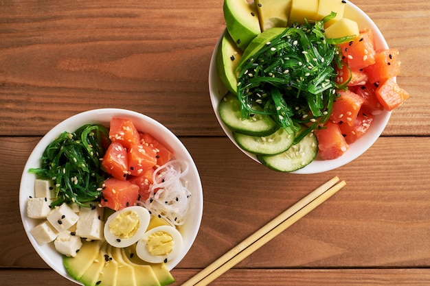 Premium Photo Raw Organic Poke Bowl With With Rice Avocado Salmon Mango Cucumbers Sweet Onions Two Plates