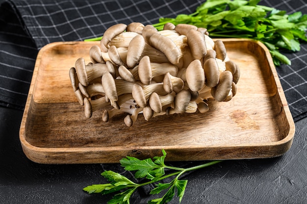 Premium Photo | Raw oyster mushrooms in a wooden bowl with parsley ...