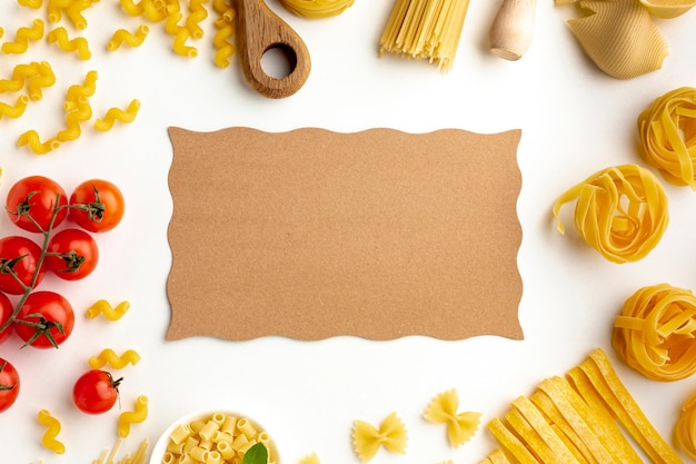 Download Raw pasta assortment and tomatoes with cardboard mock-up Photo | Free Download