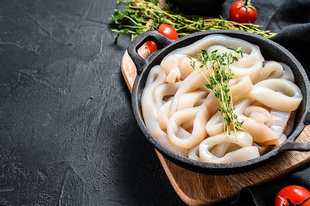 Premium Photo | Raw squid cut into rings in a frying pan. black
