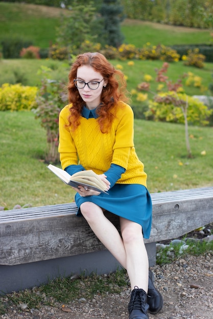 Premium Photo Readhead Girl Sitting In A Park With Book 