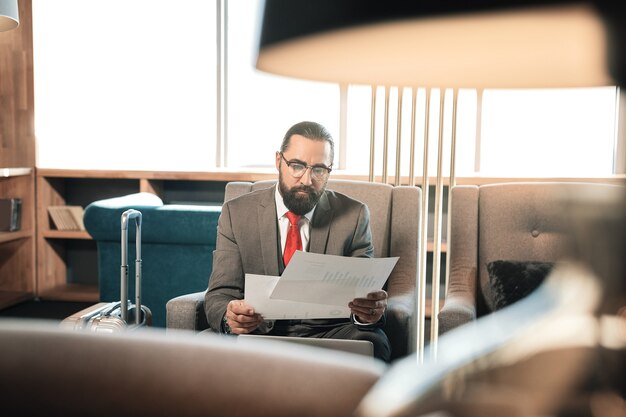 Premium Photo Reading Contract Bearded Dark Haired Mature Businessman Reading Contract Sitting In Comfortable Armchair