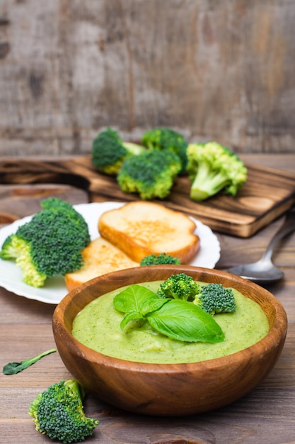 Premium Photo Ready To Eat Fresh Hot Broccoli Puree Soup With Pieces Of Broccoli And Basil Leaves In A Wooden Plate And Spoon On A Wooden Table