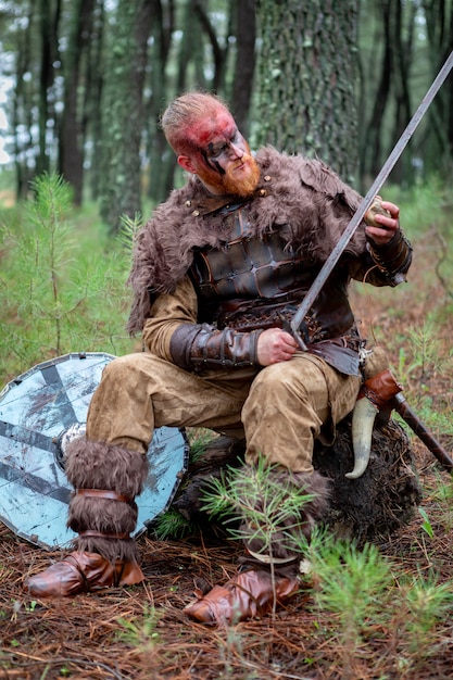 Premium Photo | Real viking sharpening his sword with a stone