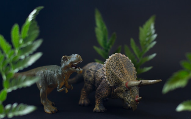 プレミアム写真 ジューシーな緑の葉の下にあるティラノサウルスとトリケラトプス恐竜のリアルな姿