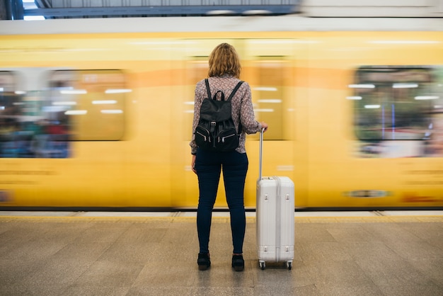 Rear view of a blond woman waiting at the train platform Free Photo