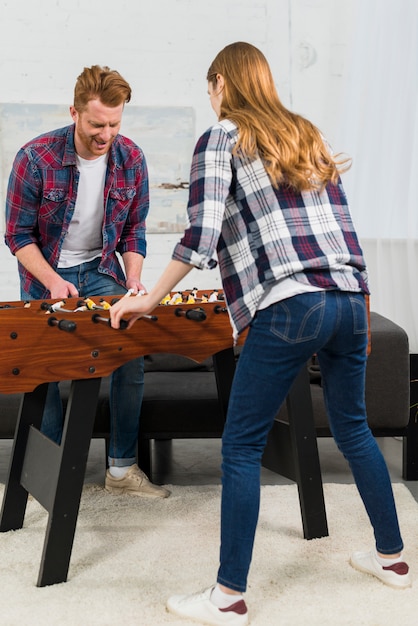 Rear view of couple enjoying the table soccer game at home Free Photo