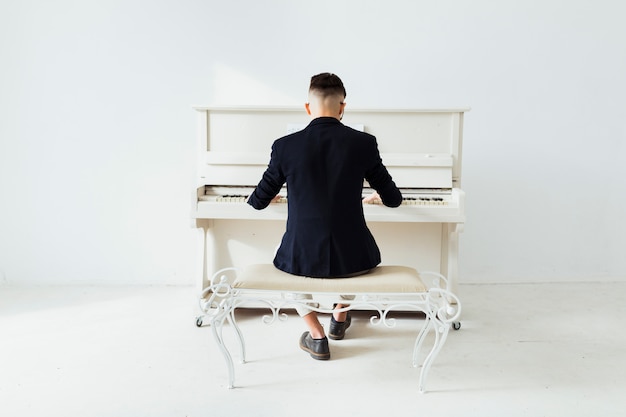 Free Photo | Rear view of a man playing the piano sitting against white ...