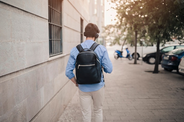 Free Photo | Rear view of a man with black backpack walking on pavement