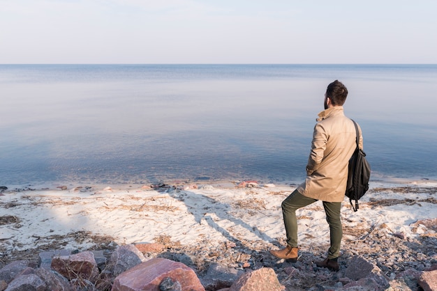 穏やかな海の景色を見て男性の旅行者の後姿 無料の写真