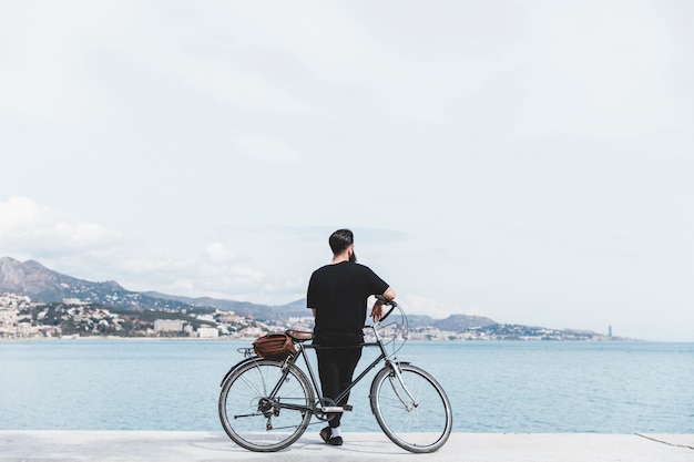 海を見て自転車で立っている若い男の後姿 プレミアム写真