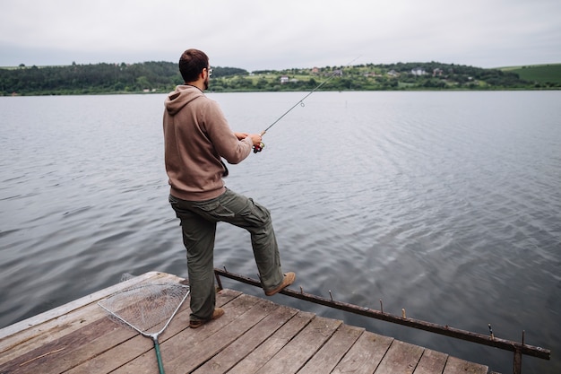 湖での桟橋釣りに立っている男の後姿 無料の写真