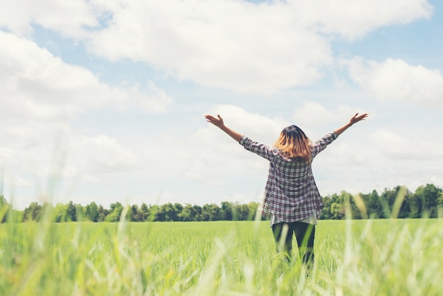 Rear view of young woman with open arms in the meadow Free Photo