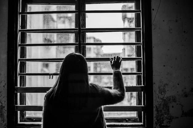 Rear view of sad woman next to the window | Free Photo