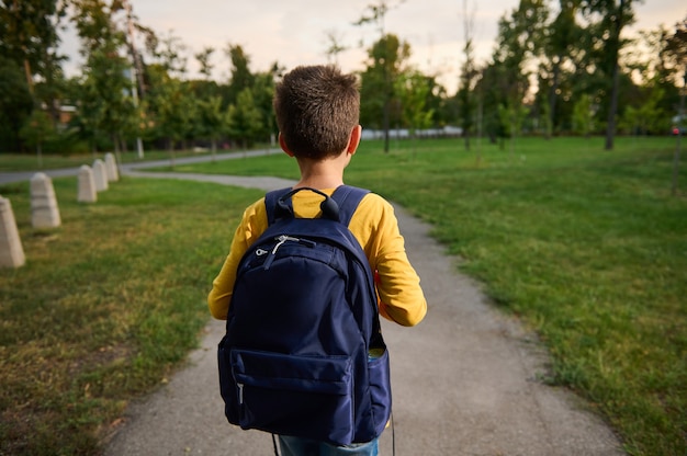 Premium Photo | Rear view of a schoolboy with schoolbag backpack ...