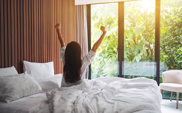 Premium Photo Rear View Of A Woman Do Stretching After Waking Up In The Morning Looking At A Beautiful Nature View Outside Bedroom Window