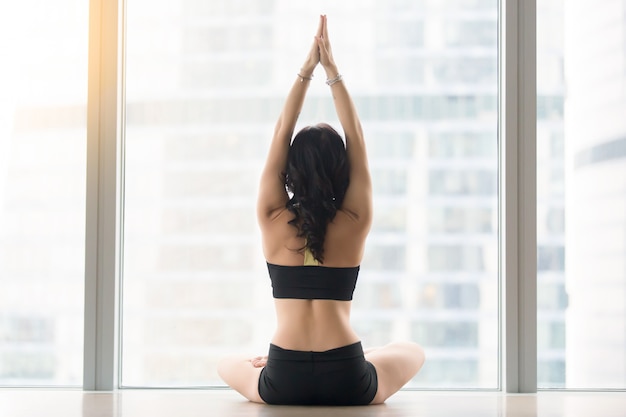 Rear view of young woman sitting in ardha padmasana pose Free Photo