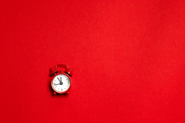 Red alarm clock in a minimal style on a red background. flat lay. holiday concept Premium Photo