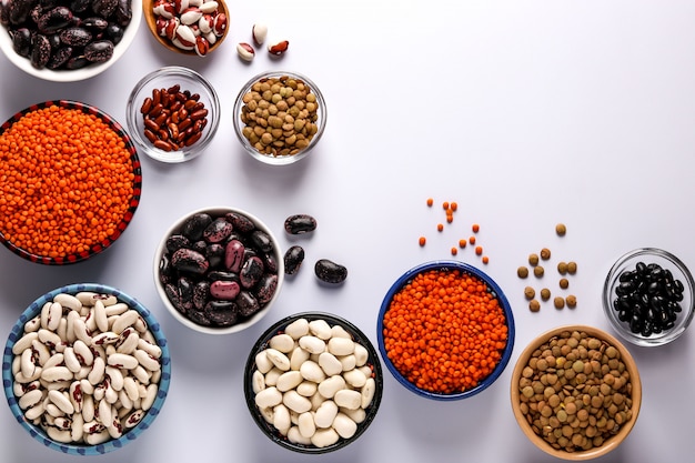 赤と茶色のレンズ豆 黒 茶色と白の豆は 白い背景のボウルにあるタンパク質の多くを含む豆類です プレミアム写真