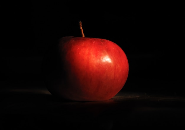 Premium Photo | Red apple in the darkness