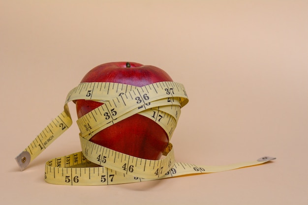 Premium Photo | Red apple wrap by measuring tape to measure length on a ...