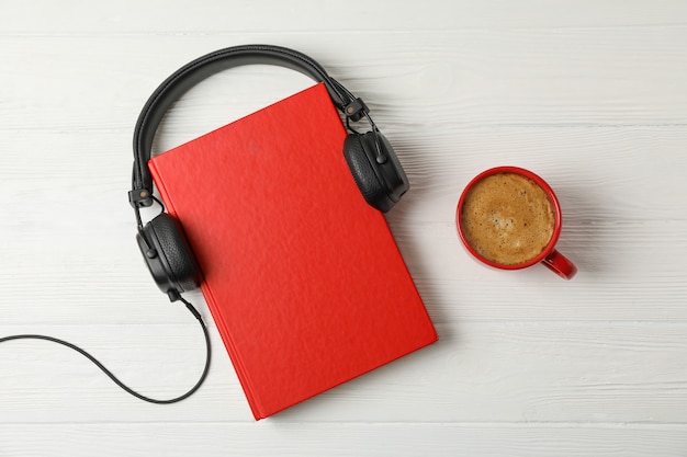  Red book, headphones and coffee cup on wooden space, space for text