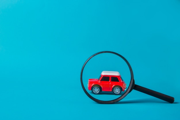 赤い車は青色の背景に虫眼鏡で覗き見 技術検査と機械検索 プレミアム写真