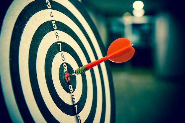Premium Photo | Red dart arrow hitting in the target center of bulls eye.