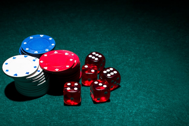Red dices and casino chips stack on green poker table Free Photo
