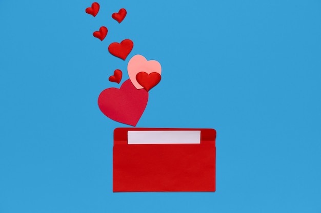 ラブレターと周りにたくさんの心を持つ赤い封筒 ハートが封筒から注がれます ラブレター 愛の概念 プレミアム写真