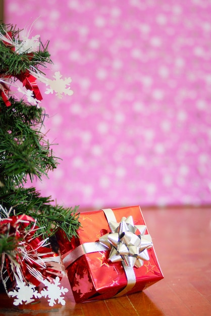 Premium Photo | A red gift box with christmas tree on pink background.
