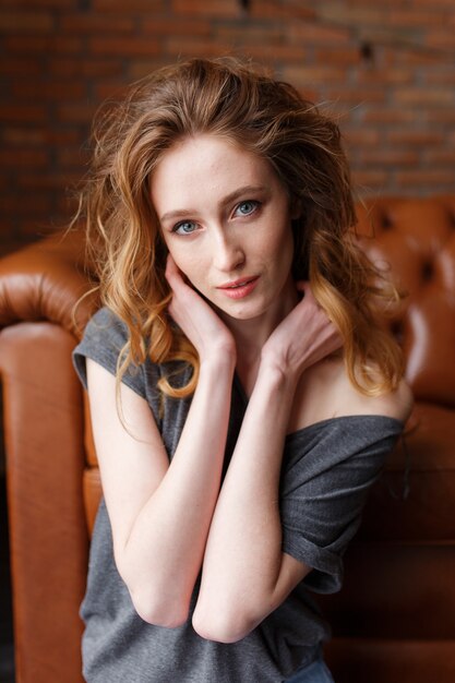 Red hair woman portrait. Brick loft wall on background. Serie Free Photo