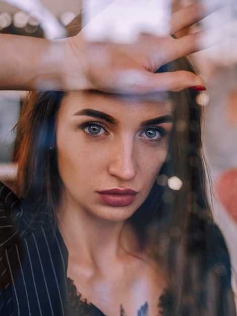 Premium Photo | Red haired girl behind the glass looks at the camera