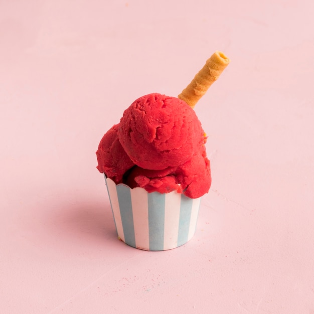 Red ice cream scoop with waffle straw in striped bowl | Free Photo