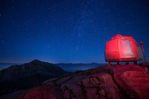 美しい星空の下で背の高い山々の赤い点灯ビバーク 無料の写真