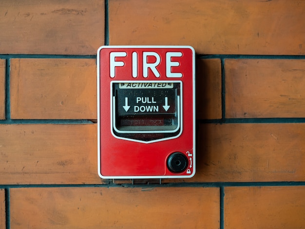 Premium Photo | Red manual fire alarm on brick wall