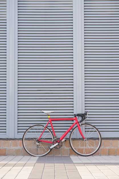 赤いロードバイクは灰色の壁の上に立つ プレミアム写真